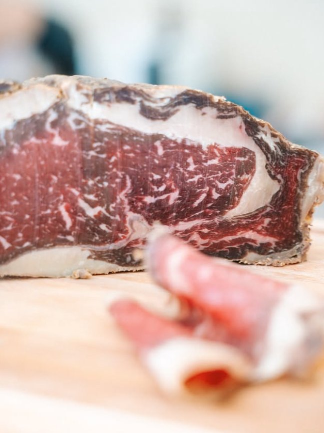 Coppa italienne tranchée finement, persillage marbré, sur planche de bois