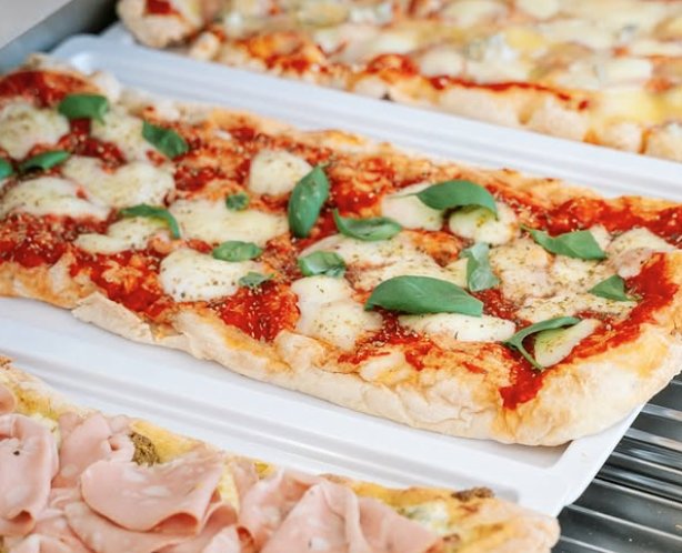 Pizzas al taglio à la tranche, plaque garnie de mozzarella, basilic et tomates